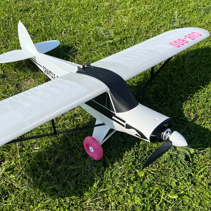 Avión blanco radiocontrolado impreso en 3D sobre el pasto